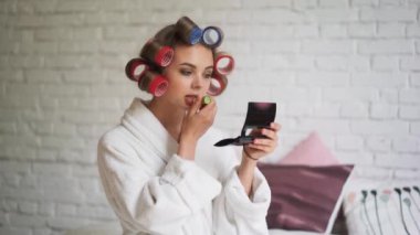 Sabahları banyo sonra curlers içinde güzel bir kız dudaklarını boyalar