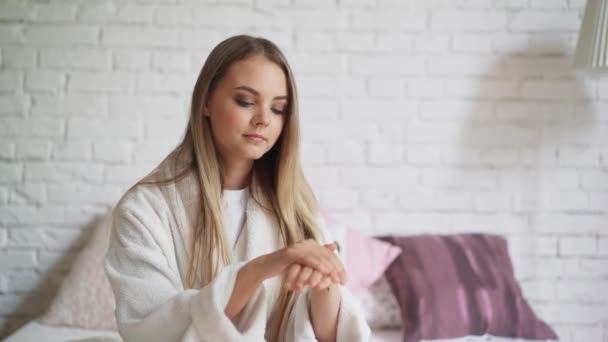 Ragazza carina in accappatoio si strofina le mani con la crema — Video Stock