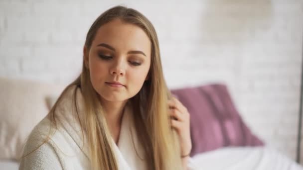 Uma mulher com o cabelo emaranhado marrom grosso está tentando pentear seu cabelo, mas não . — Vídeo de Stock