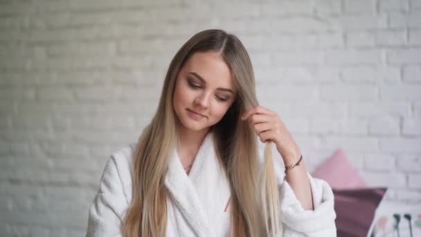 Όμορφο κορίτσι που κάθεται στο κρεβάτι υπνοδωμάτιο ανατροπές σίδερα, όμορφη, υγιή μαλλιά — Αρχείο Βίντεο