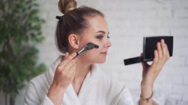 Kafasında havluyla gülen genç bir kız yüzüne siyah bir maske takıyor.