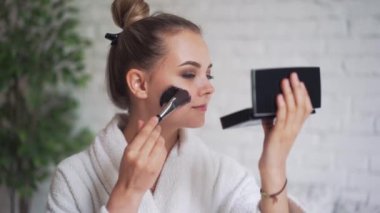 Kafasında havluyla gülen genç bir kız yüzüne siyah bir maske takıyor.