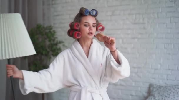 Feliz jovem loira mulher whith cabelo muito longo no pijama pulando e dançando na cama de manhã e sorrindo. Mulher de humor alegre — Vídeo de Stock