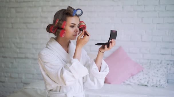 Makeup ung kvinna sätta läppstift bär Hårrullar sig redo för att gå ut. — Stockvideo