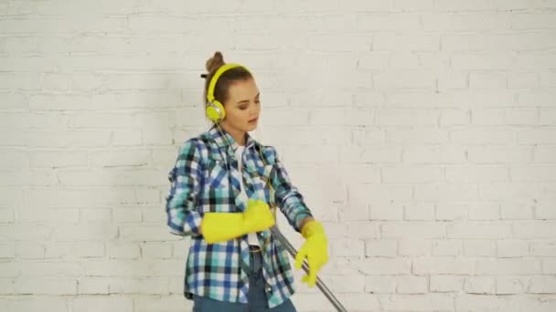 Kulaklığı ve MOP 'u olan genç bir kadın ev temizliğine hazır. İyi bir müzikle dans edip şarkı söylemek. — Stok video