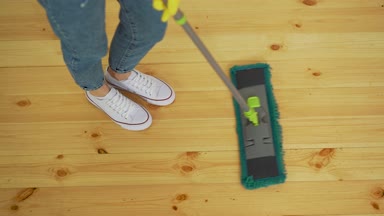 Güzel genç kadının koruyucu eldiven kat evde temizlik yaparken düz bir ıslak bez kullanarak kırpılmış görüntü