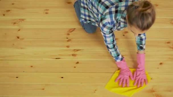 Mujer concentrada puliendo suelo de madera. Chica joven en guantes de protección lavado apartamento, concepto de limpieza de primavera, espacio para copiar — Vídeo de stock