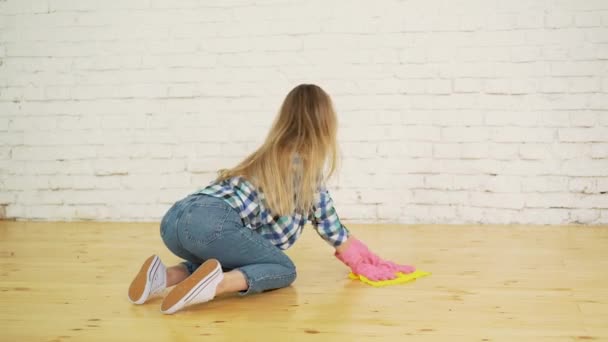 Geconcentreerde vrouw houten vloer te polijsten. Jong meisje in beschermende handschoenen wassen appartement, lente schoonmaak concept, kopie ruimte — Stockvideo