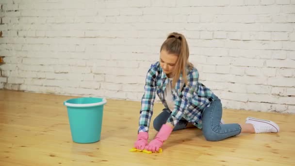 Shocked woman cleaning house with lots of tools. Young tired girl throws a rag in a bucket. — Stock Video