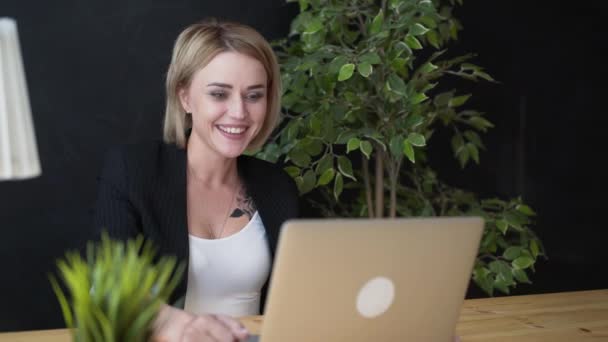 Κομψό θετική όμορφη κοπέλα κάθεται χρησιμοποιώντας το φορητό υπολογιστή σε ένα καφέ — Αρχείο Βίντεο