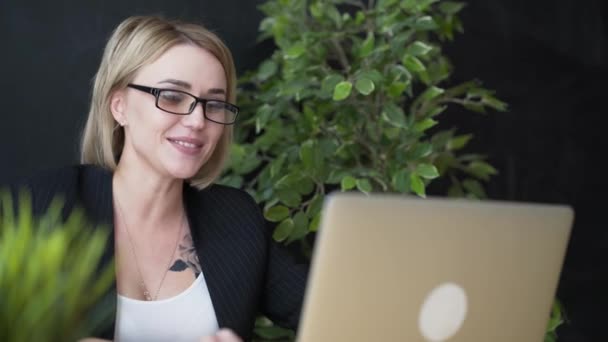 Eleganta unga positiva vackra flicka sitter använder bärbar dator på ett kafé — Stockvideo