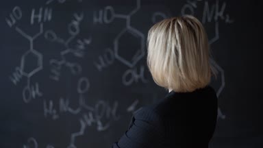 Formülleri ile tahta yakınındaki ayakta zor bir görev çözme bir kadın portresi. Bilim kavramı. Düzen.