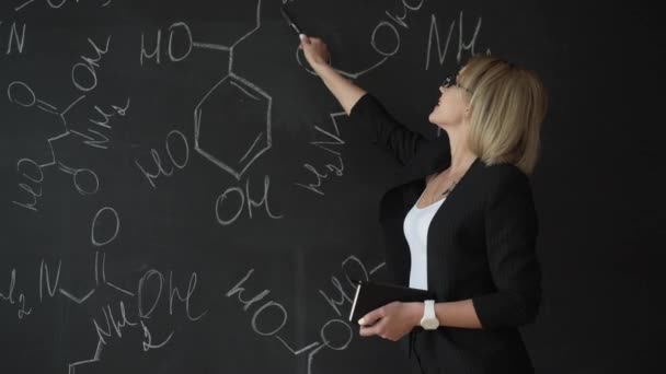Lärare skriver formler på krita styrelsen och förklarar eleverna formeln. — Stockvideo