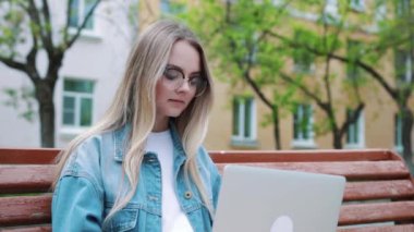 Genç kız bir dizüstü bilgisayar ile bir bankta. Öğrenci sınav için hazırlar.