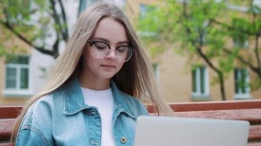 Genç kız bir dizüstü bilgisayar ile bir bankta. Öğrenci sınav için hazırlar.