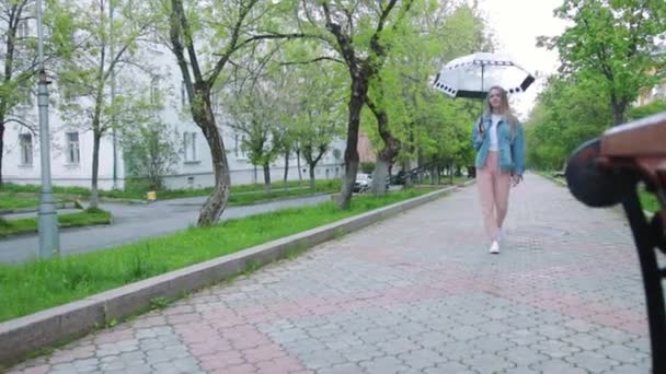 Menina caminhando sob um guarda-chuva na chuva — Vídeo de Stock