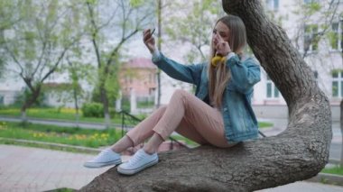 Parkta fotoğraf çeken gülümseyen genç bir kızın portresi.