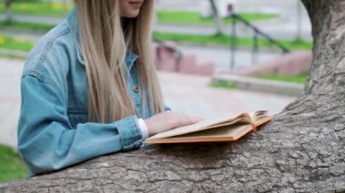 Güzel ciddi kız kot ceket ve gözlük okuma kitap yaz yeşil park karşı