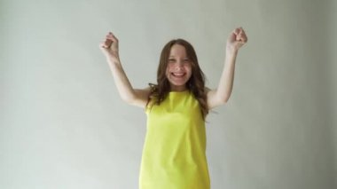 Gri arka plan üzerinde şehvetli dudakları ile duygusal bir kız. Parlak sarı elbiseli çekici esmer portresi