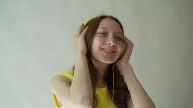 Güzel gülümseyen esmer gri arka plan üzerinde Studio kulaklık kullanarak müzik dinler.