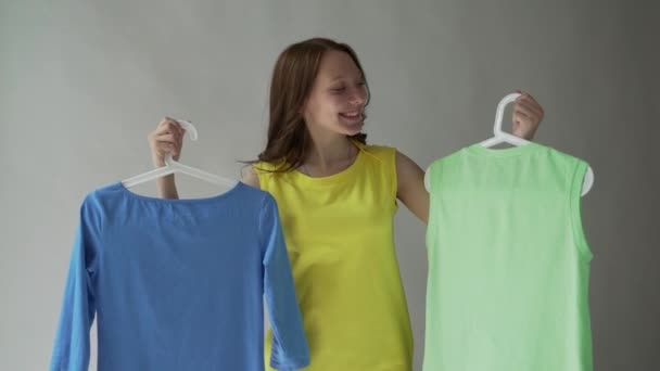 Fiatal, gyönyörű nő kipróbálás-hoz választ ruhák. — Stock videók