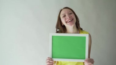 Gri bir arka plan üzerinde ellerini chromakey işaretli bir çekici kadın.