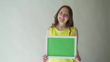 Gri bir arka plan üzerinde ellerini chromakey işaretli bir çekici kadın.