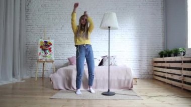 Evde kulaklıkla müzik dinleyen güzel genç bir kadın.