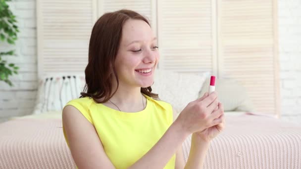 Ragazza blogger con rossetto si siede sul divano e guarda la macchina fotografica fashion blogger scatta video dalla fotocamera con un treppiede . — Video Stock