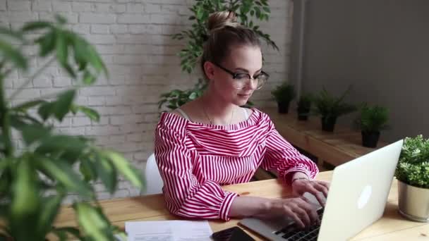 Χαμογελά ευτυχισμένη επιχειρηματία που κάθεται στο τραπέζι, κοιτάζοντας την οθόνη του laptop, έχοντας μια κλήση βίντεο. Νέοι επαγγελματίες κυρία έχοντας μια κλήση βίντεο. Μια όμορφη γυναίκα που εργάζεται για το laptop της. — Αρχείο Βίντεο