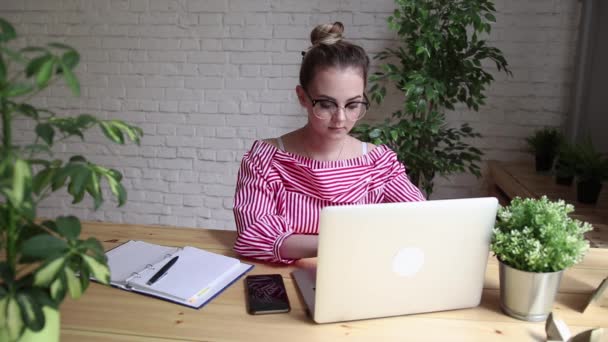 Empresário feliz sorrindo sentado à mesa, olhando para a tela do laptop, tendo uma chamada de vídeo. Uma jovem empresária a fazer uma videochamada. Uma mulher bonita está trabalhando em seu laptop . — Vídeo de Stock