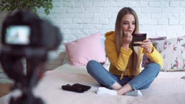 Komik kadın video blogger kayıt. Yatağın üzerinde oturan kız güzellik blogger yazıyor bir video blog.