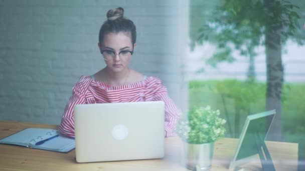 Concepto pensativo. Mujer trabajando en una computadora en un café mientras mira a través del cristal de la ventana . — Vídeos de Stock