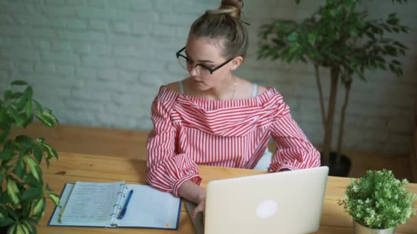 Kvinnan sitter på jobbet på bordet framför en bärbar dator, kvinnliga händer på tangentbordet — Stockvideo