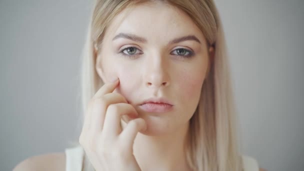 A linda garota loira olha para a câmera, de perto. A menina abre os olhos para a câmera — Vídeo de Stock