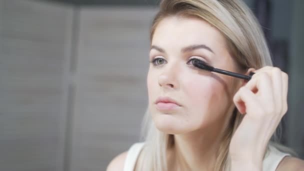 Молодая красивая женщина наносит макияж на веки кистью — стоковое видео