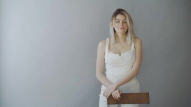 Gri arka plan üzerinde duran ve kameraya bakarak mutlu çekici kız