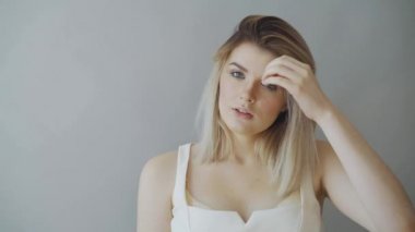 Gri arka plan üzerinde duran ve kameraya bakarak mutlu çekici kız