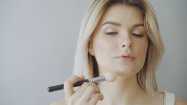 Make-up. Ung vacker flicka att göra makeup med borste på kinderna. — Stockvideo