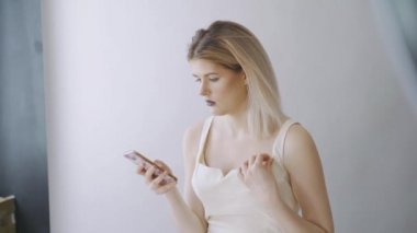 Genç güzel kız Smartphone cep telefonu ile fotoğraf izliyor, o taşınır, iletişim kavramı, gri arka plan