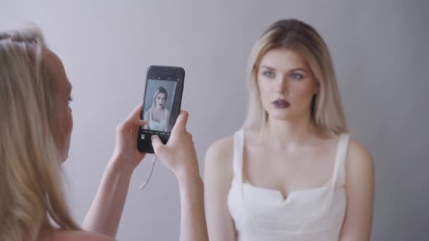 Makeup artist takes pictures of the model on the phone. Dark lips, gray background. Makeup — Stock Video