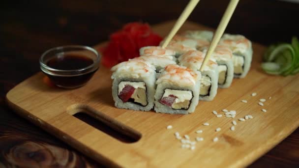 Des sushis frais, des rouleaux sur la table. Fond sombre. Bâtonnets de sushi . — Video
