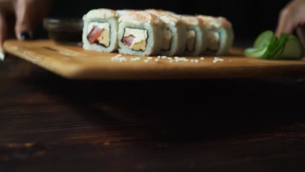 Friss sushi tekercs az asztalon. Sötét háttér előtt. Sushi botok. — Stock videók