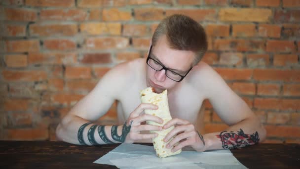 Joven, estudiante sentado en casa comiendo comida rápida. Shawarma, Shawarma, Shawarma. Alimentos frescos saludables o poco saludables . — Vídeo de stock