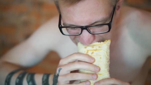 Joven, estudiante sentado en casa comiendo comida rápida. Shawarma, Shawarma, Shawarma. Alimentos frescos saludables o poco saludables . — Vídeo de stock