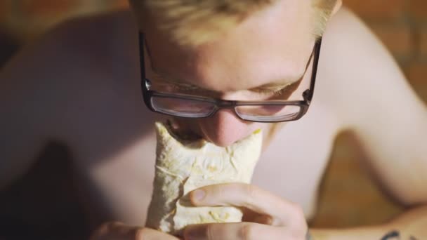 Mladý muž, student sedí u domů jíst fast food. Shawarma, Shawarma, Shawarma. Zdravá nebo nezdravá čerstvé potraviny. — Stock video