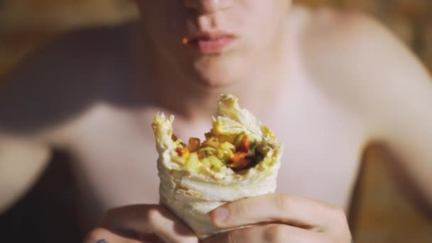 Joven, estudiante sentado en casa comiendo comida rápida. Shawarma, Shawarma, Shawarma. Alimentos frescos saludables o poco saludables . — Vídeos de Stock