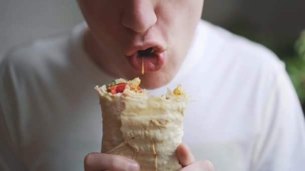 Joven, estudiante sentado en casa comiendo comida rápida. Shawarma, Shawarma, Shawarma. Alimentos frescos saludables o poco saludables . — Vídeo de stock