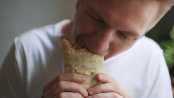 Joven, estudiante sentado en casa comiendo comida rápida. Shawarma, Shawarma, Shawarma. Alimentos frescos saludables o poco saludables . — Vídeo de stock