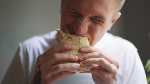 Young man, student sitting at home eating fast food. Shawarma, Shawarma, Shawarma. Healthy or unhealthy fresh food. — Stock Video